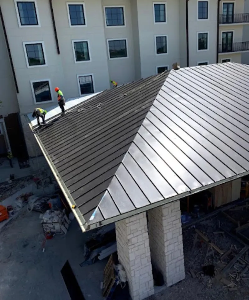 Crew installing standing seam metal roof panels on a commercial project in Artesia